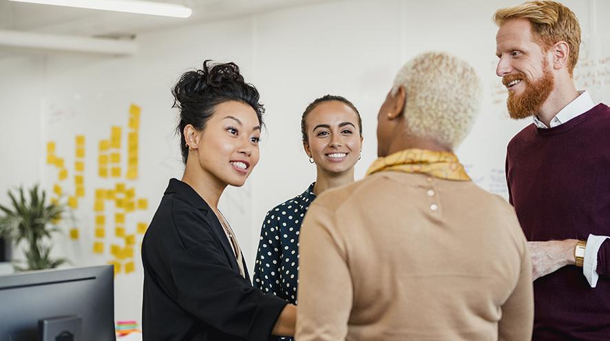 Group of women and men chatting in an office.