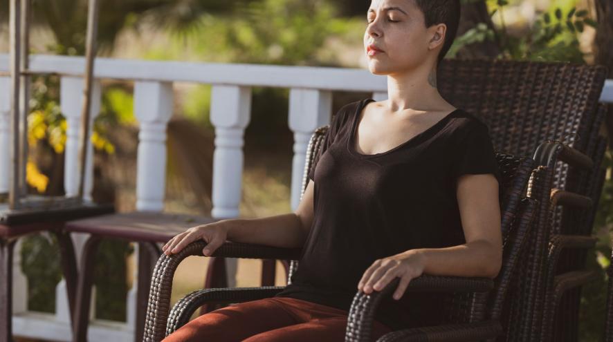 A woman relaxing and leaning back in a chair with her eyes closed.