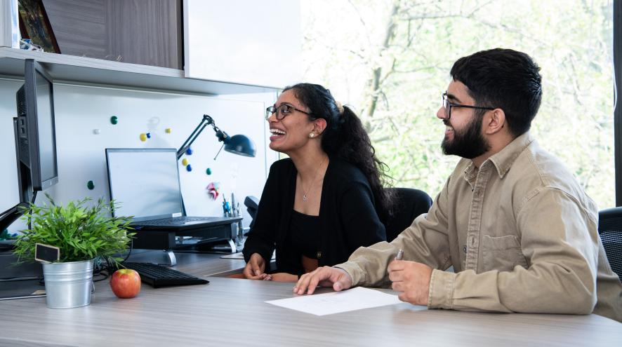 photo of two people smiling at a computer screen