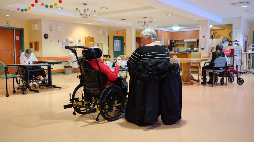 A mother and daughter sitting in a well-lit long-term care home.