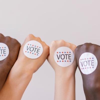 Four hands with stickers reading vote