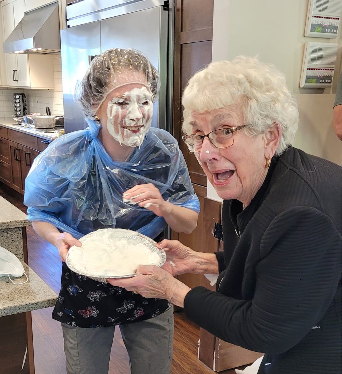 Photo of a woman hitting one of the female Grass Home employees with a pie in the face