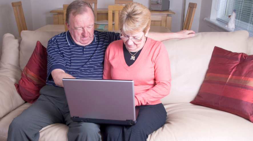 Man and woman using laptop while sitting on couch