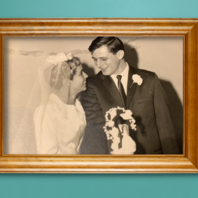 A photo of Maggie and Don on their wedding day in a wooden frame, hanging on a teal wall.