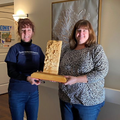 Photo of ASNB staff member presenting Grass Home Staff member with the forget-me-not trophy