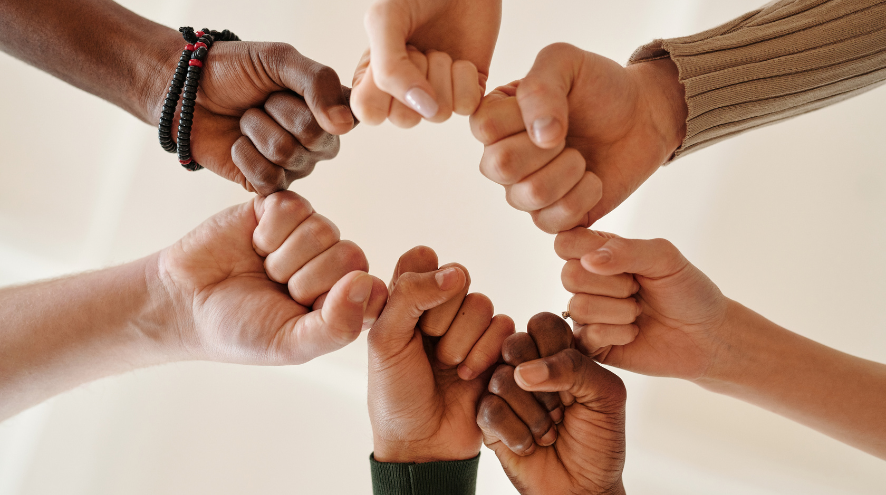 Seven set of hands meeting in the middle to bump fists