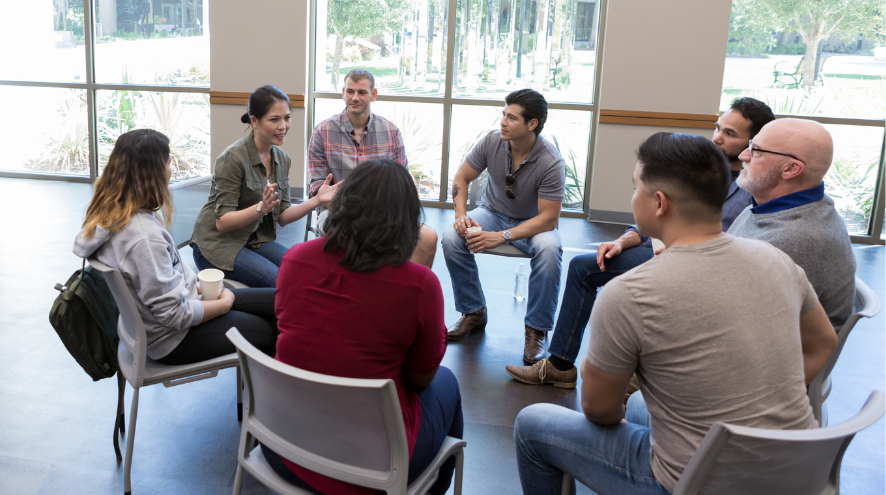 Eight people sitting in circle speaking to one another 