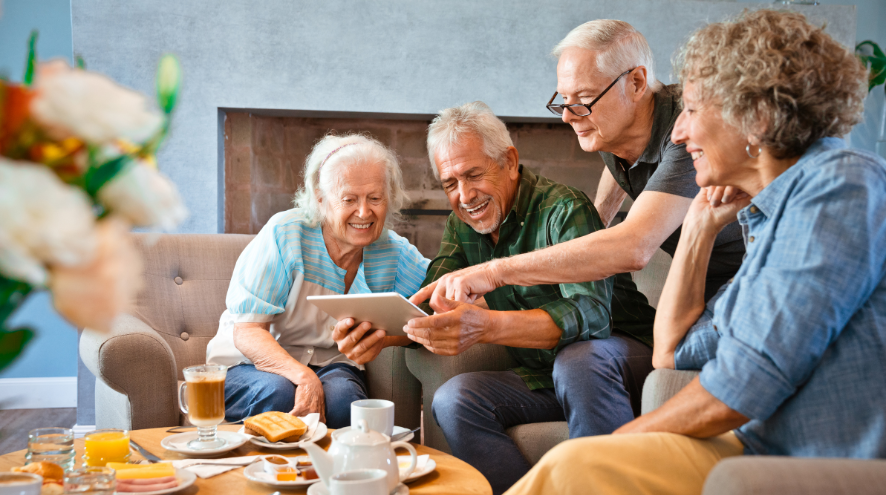 Four people seated and looking at tablet