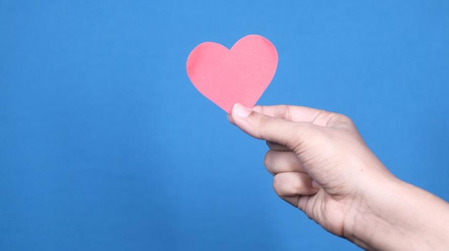 hand holding a pink paper heart