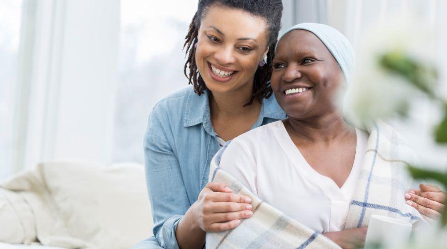 A daughter holds her mother close while both smile
