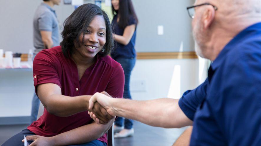 a woman shakes the hand of an older man