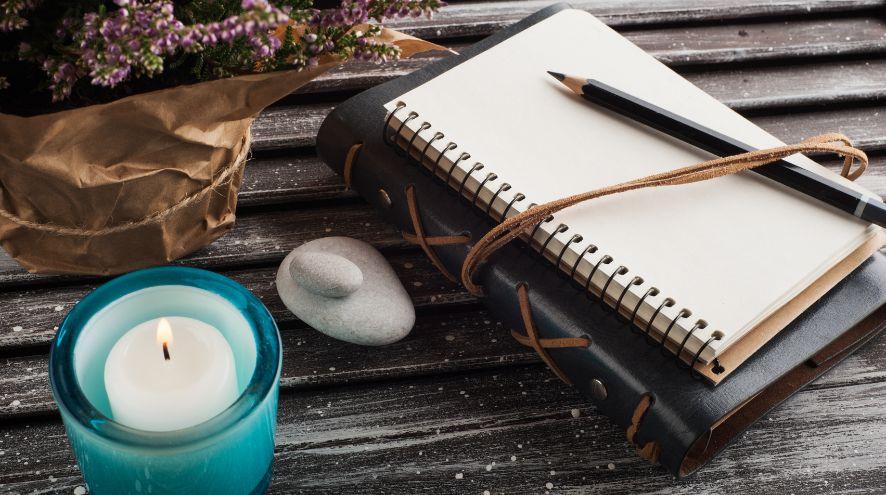 Two journals on a table beside a candle