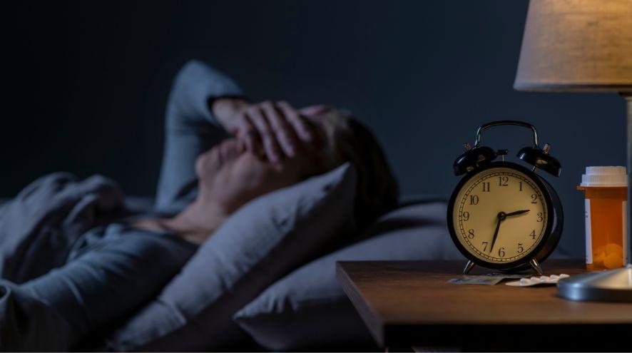 A person laying in bed struggling to sleep