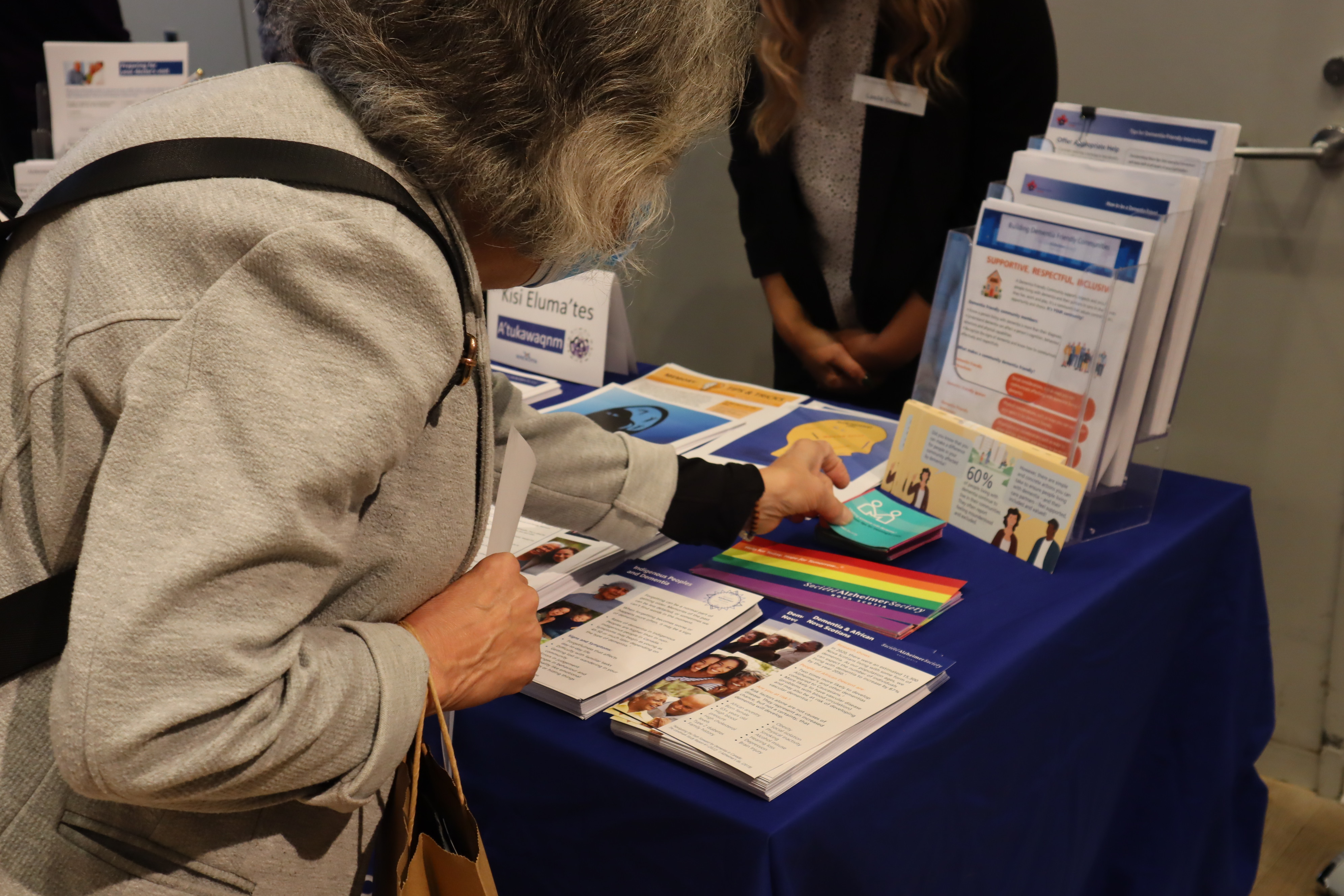 A woman reaches for informational materials on a table. 