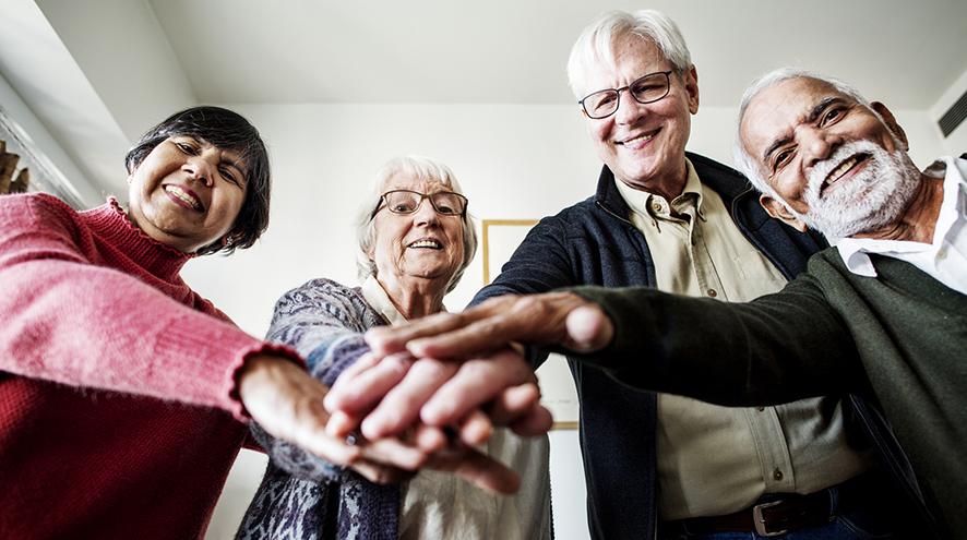 Group of people looking at the camera with their hands together at the centre of the group