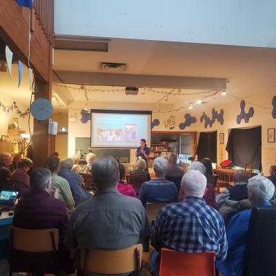 A group of people sit and watch a dementia presentation on a projected screen in a small room