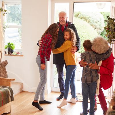 Excited Grandchildren Greeting Grandparents With Presents Visiting During Holidays