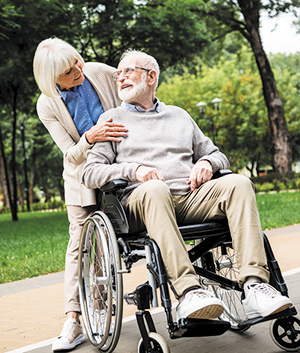 Man in wheelchair, woman standing behind him hugging him