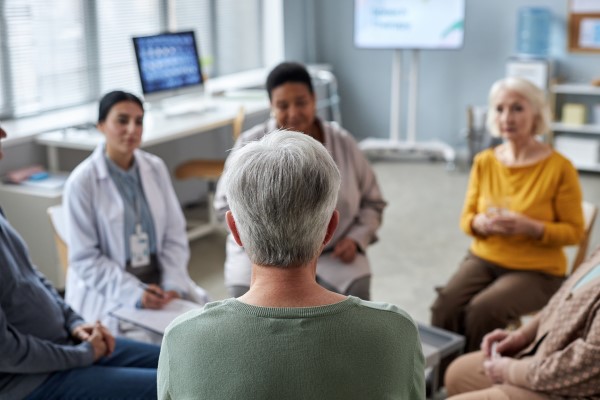 Senior woman sitting in circle at support group in retirement home