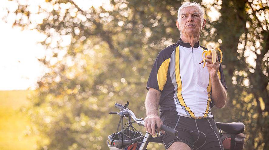 Senior cyclist eating a banana.