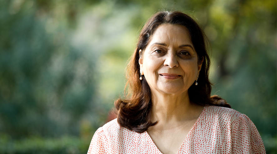 Midlife woman smiling warmly in an orange and white blouse