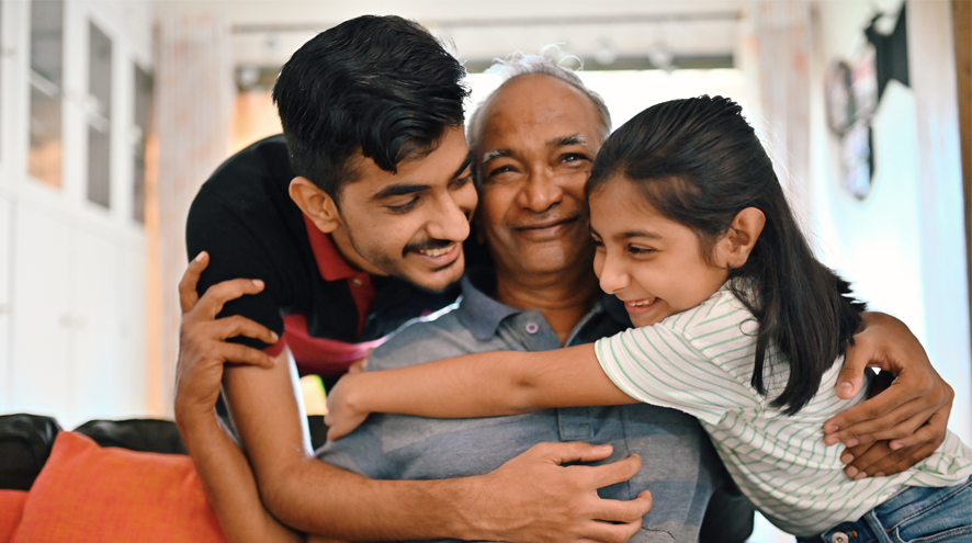 Older man being embraced by a child and a teenager