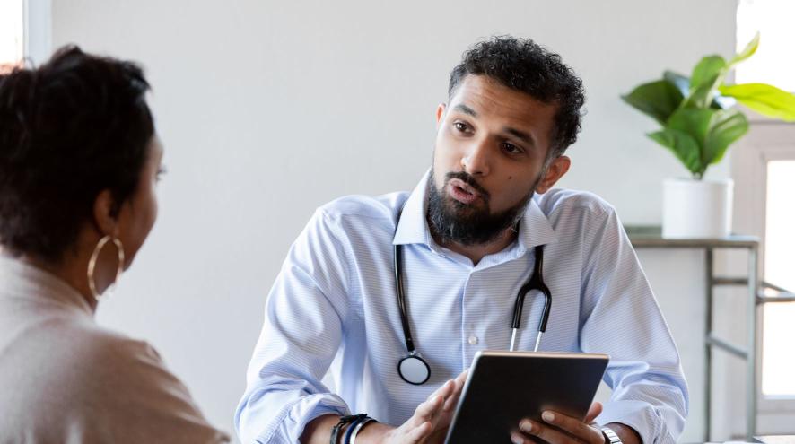 Doctor with stethoscope and tablet speaks with a patient