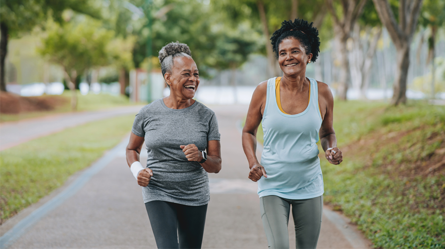 Two women running outdoors and smiling