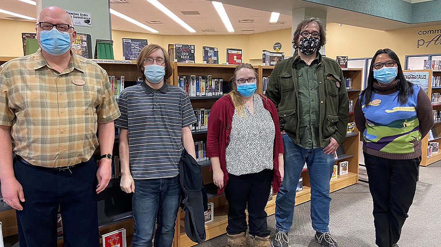 Our Dementia Community Coordinator with Yorkton Public Library staff members standing in front of a book shelf.