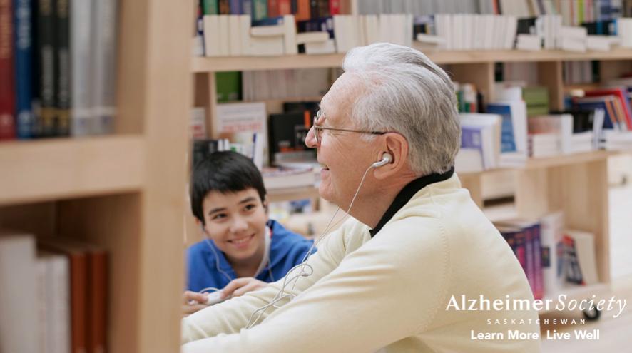 A child watching his grandfather enjoy the media center at the library.