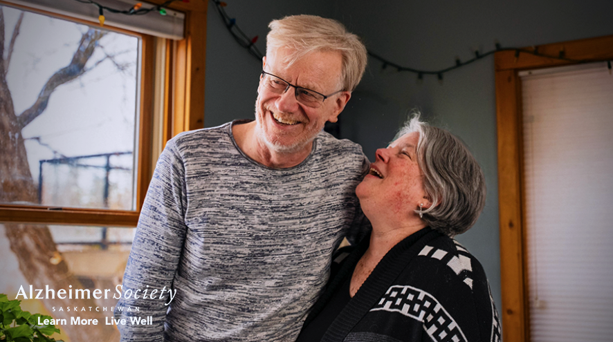 Eric Eggertson and Kelley Jo Burke are hugging each other and laughing together. Kelley Jo is looking up at Eric fondly..
