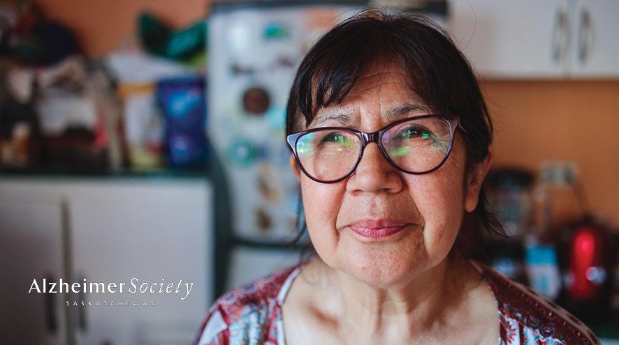 Image depicts older woman with glasses looking at the camera