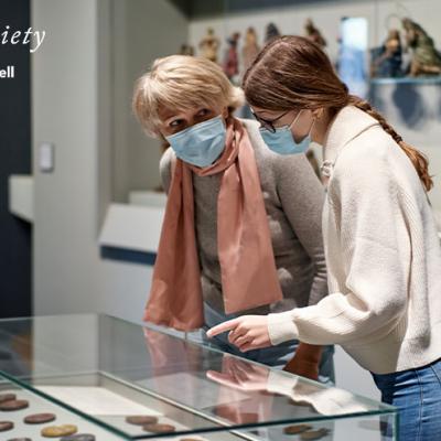 A museum guide explaining an exhibit to a senior citizen.