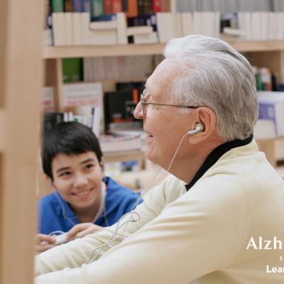A child watching his grandfather enjoy the media center at the library.