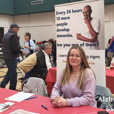 Our practicum student at our information booth with several resources ready to hand out