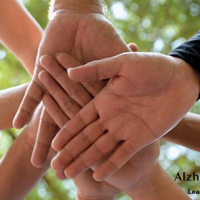 A stack of hands together in an outdoor team huddle.