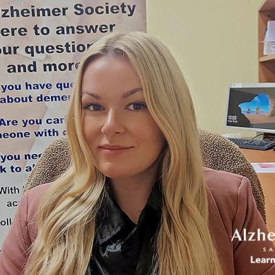 A photo of our summer practicum student in front of an Alzheimer Society banner.