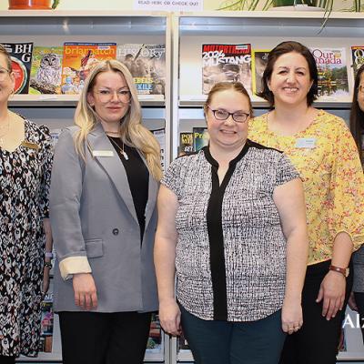 Alzheimer Society and Yorkton Public Library staff standing in front of a magazine rack.