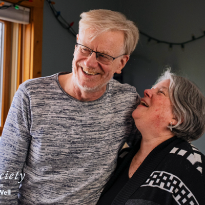Eric Eggertson and Kelley Jo Burke are hugging each other and laughing together. Kelley Jo is looking up at Eric fondly..