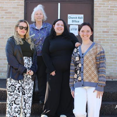 Four individuals standing outside of a church with a "Dementia in the Community Presentation" poster in the background.